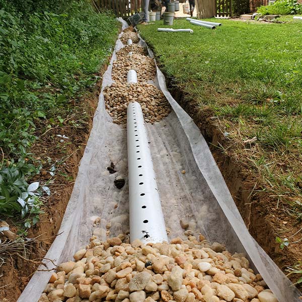 Trench with a white drainage pipe across the front patio